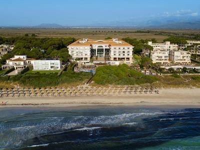 Widok na plażę z parasolami i hotelami w tle pod jasnym niebem.