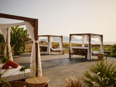Luxurious outdoor canopy beds at sunset surrounded by lush greenery.