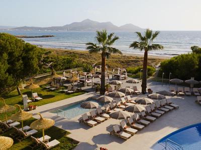 Hotel pool area with sun loungers and a view of the sea and distant mountains.