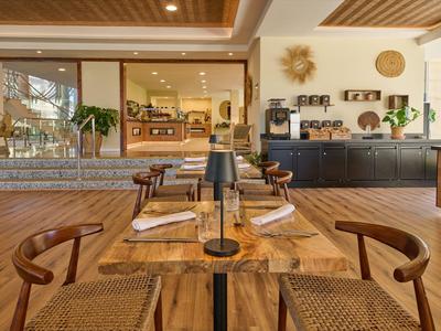 Área de comedor moderna con mesa y sillas de madera en un restaurante de hotel luminoso.