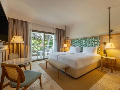 Habitación de hotel moderna con cama doble, balcón y luces cálidas.
