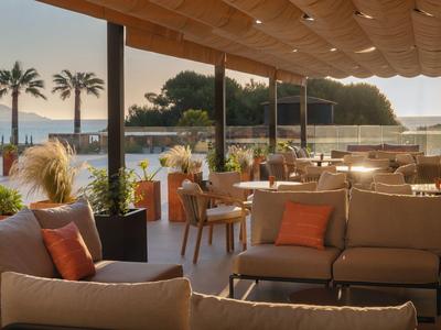 Terraza abierta con asientos cómodos y vista al mar al atardecer.