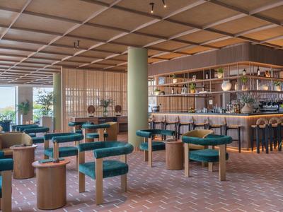 Restaurante moderno de hotel con bancos verdes y mobiliario de madera clara.