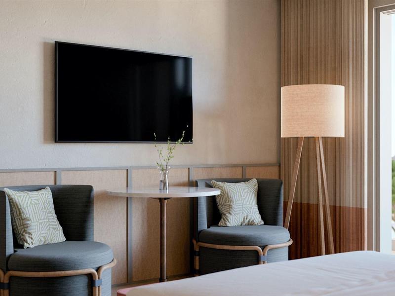 Nowoczesny kąt pokoju hotelowego z dwoma fotelami, telewizorem i dużym oknem z widokiem.