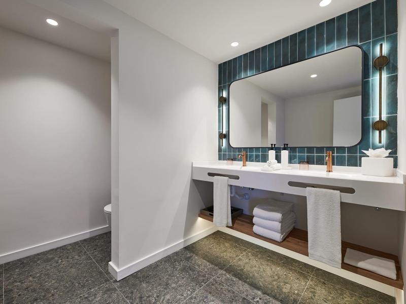 Nowoczesna łazienka z podwójną umywalką, dużym lustrem i ręcznikami pod blatem.