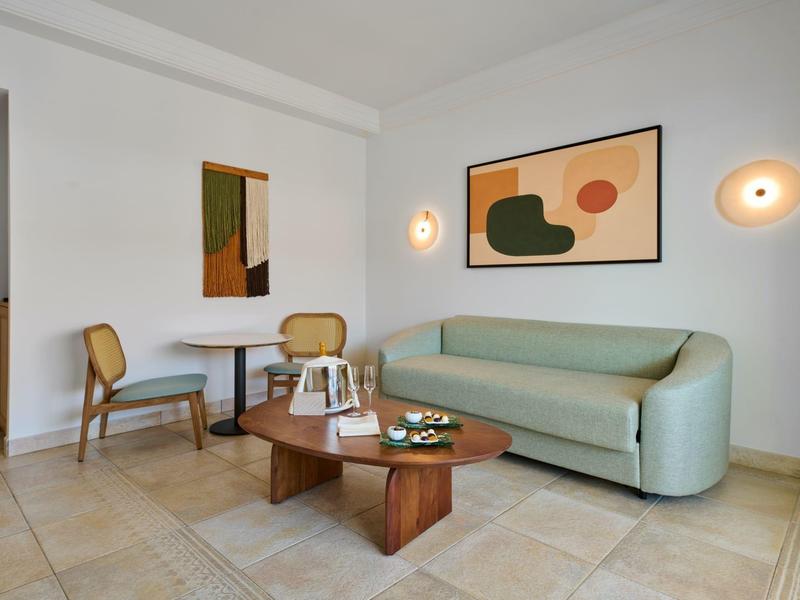 Jasny salon z nowoczesną sofą, drewnianym stołem i abstrakcyjną sztuką na ścianie.