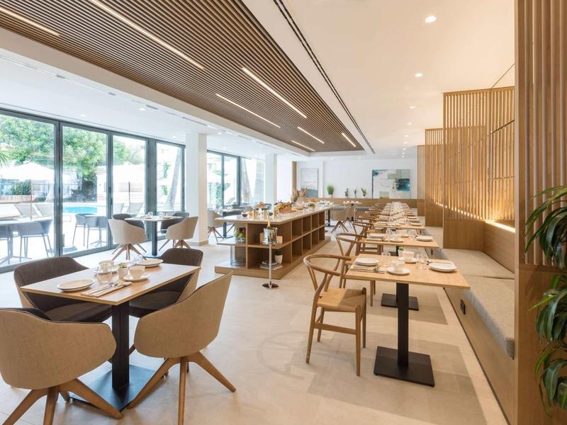 Ristorante di hotel moderno con interno luminoso e diversi tavoli apparecchiati.