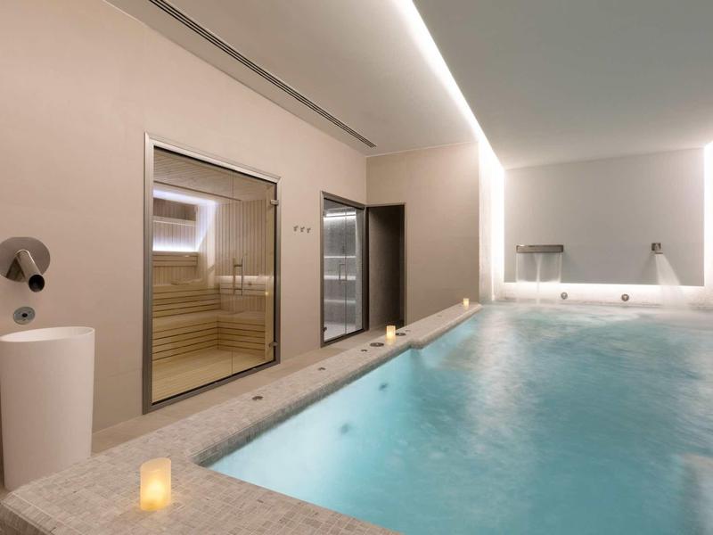Piscina interna moderna con sauna e atmosfera rilassante in una spa dell'hotel.