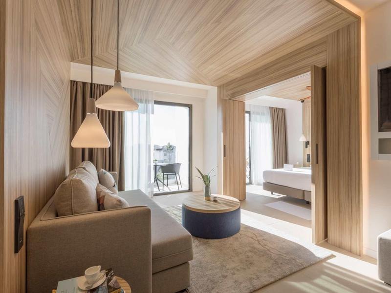 Camera d'albergo moderna con divano, tavolino e vista sul balcone e camera da letto.