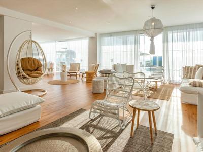 Helles, modernes Wohnzimmer mit Hängekörben, Holzfußboden und großen Fenstern.