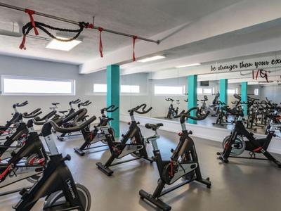 Fitnessraum mit mehreren Ergometern und großer Spiegelwand.