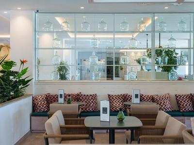 Modern eingerichteter Lounge-Bereich mit Sitzgelegenheiten und Pflanzen in einem Hotel.