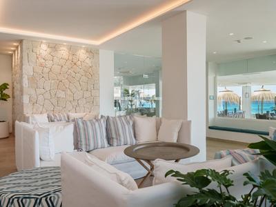 Modern eingerichteter Lounge-Bereich mit bequemen weißen Sofas und dekorativen Kissen in einem Hotel.