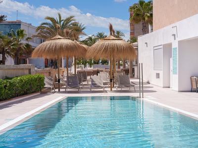 Moderner Hotelpool mit Strohschirm-Sonnenschutz und weißen Wänden bei sonnigem Wetter.