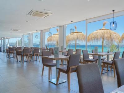 Modernes Restaurant mit Stühlen und Tischen sowie großer Glasfront zum Meer hin