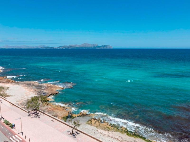 Küstenpromenade entlang eines klaren blauen Meeres unter einem hellblauen Himmel.