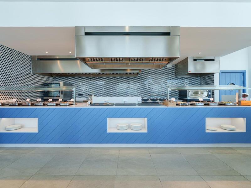 Moderne Hotelküche mit blauem Kochinsel und Edelstahlgeräten.