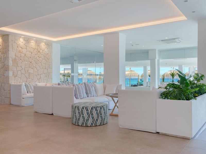 Heller, moderner Hotel-Wartebereich mit weißen Möbeln und Pflanzen.