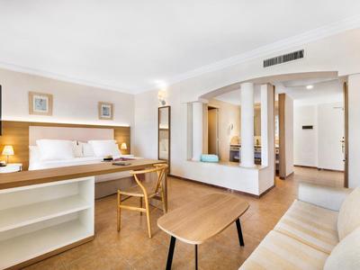 Chambre d'hôtel lumineuse avec mobilier confortable, tables et chaises en bois, design moderne.