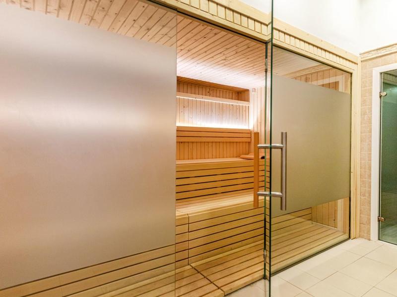 Sauna moderne avec murs en verre et bancs en bois dans un espace bien-être.