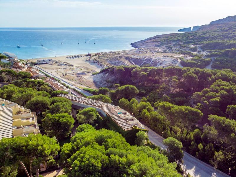 Paysage côtier avec verdure, routes et vue sur la mer et les installations portuaires.