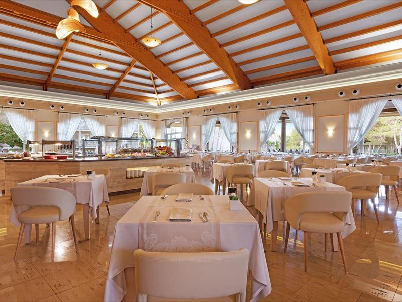 Restaurant spacieux avec plafond à poutres en bois et tables dressées.