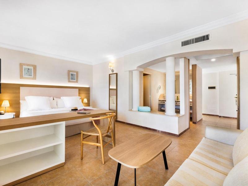 Chambre d'hôtel lumineuse avec mobilier confortable, tables et chaises en bois, design moderne.