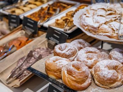 Various pastries displayed on a bakery counter, dusted with powdered sugar.