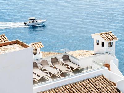 White terrace with sun loungers overlooking the sea with a boat in the background.