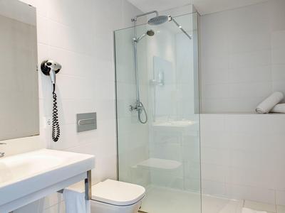 Bright, modern bathroom with glass shower, sink, and toilet.