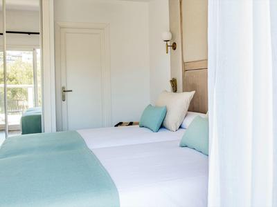 Brightly decorated hotel room with two beds and balcony view.