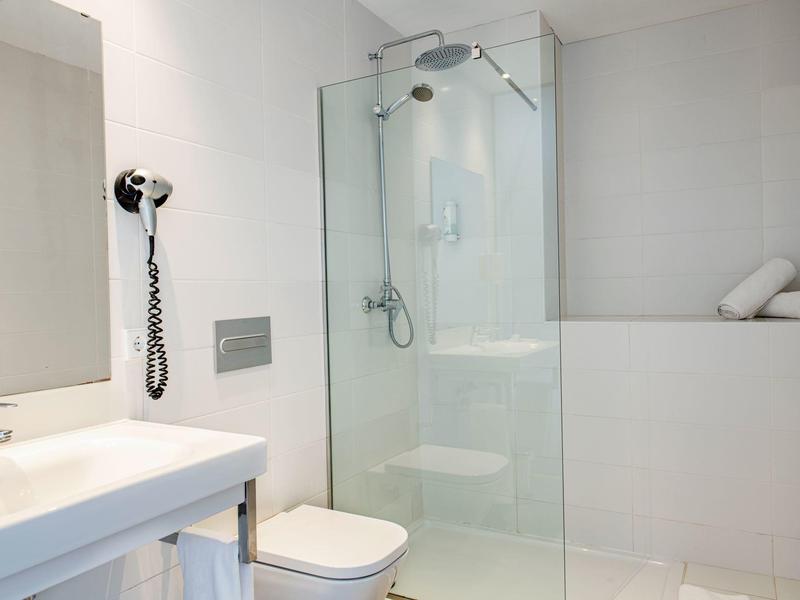 Bright, modern bathroom with glass shower, sink, and toilet.