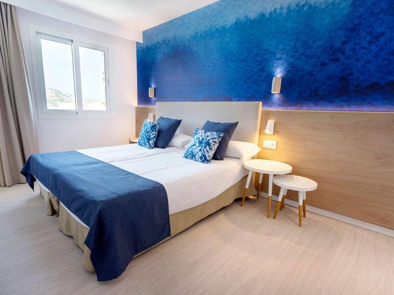 Modernes Schlafzimmer mit Doppelbett, blauen Wandfarben und minimalistischen Nachttischen.