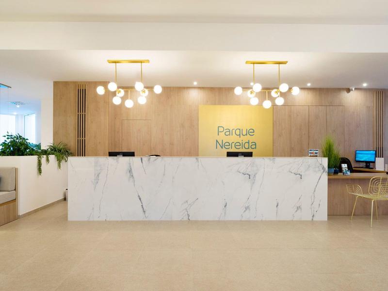 Moderne Rezeption mit weißem Marmortresen, Holzvertäfelung und heller Beleuchtung in hellem Raum.