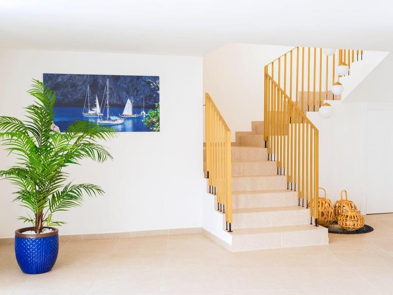 Helle Treppe mit weißen Wänden, Pflanzen in blauer Vase und Holzgeländer in modernem Raum.