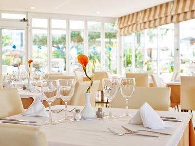 Elegantes Restaurant mit gedeckten Tischen und Blick auf eine Terrasse mit Pflanzen.