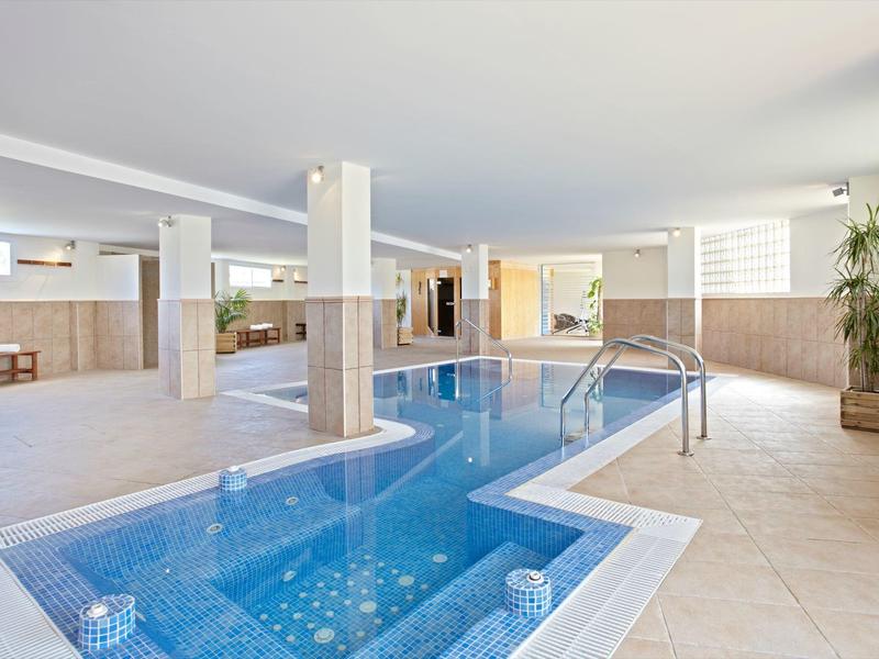 Moderner Indoorpool mit Klarglas, hellen Fliesen und großen Fenstern in einem hellen Raum.