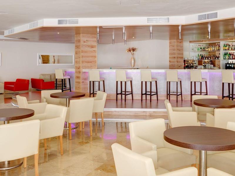 Helle Café-Lounge mit Holztheke, runden Tischen und weißen Polstersesseln in modernem Design.