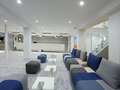Modern hotel lounge area with blue sofas and white tables in bright space