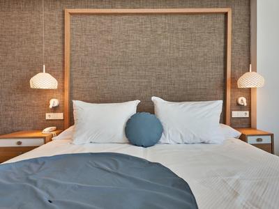 Modern hotel room with double bed, white and blue bedding, and hanging bedside lamps