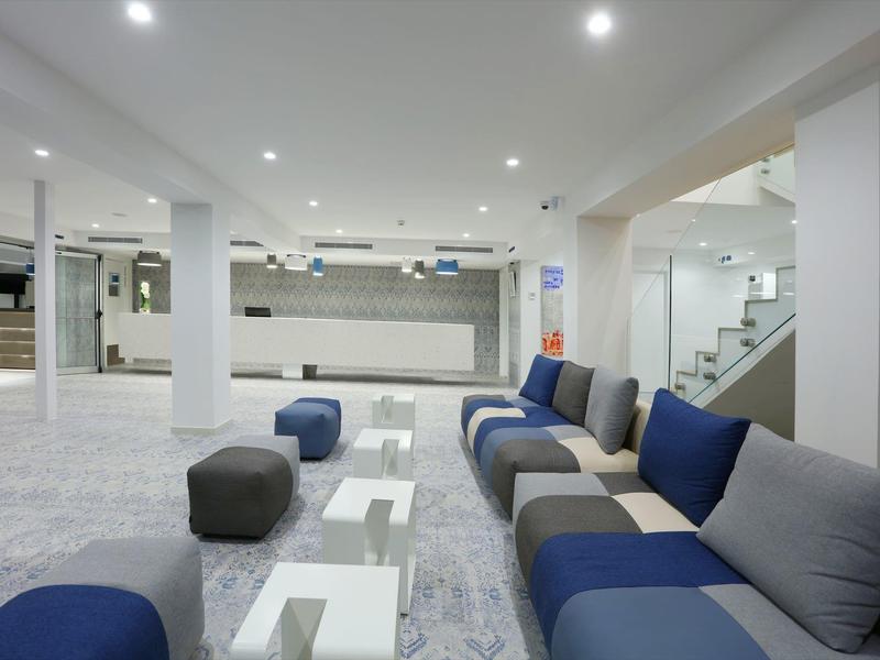 Modern hotel lounge area with blue sofas and white tables in bright space