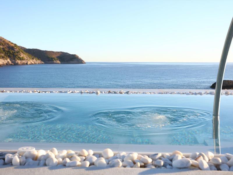 Infinity pool with bubbles and view of the sea and hills in the background