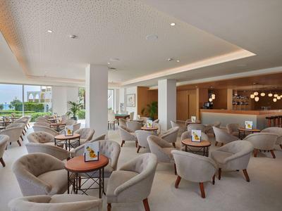 Modern hotel lounge with comfortable armchairs and large windows overlooking the garden.