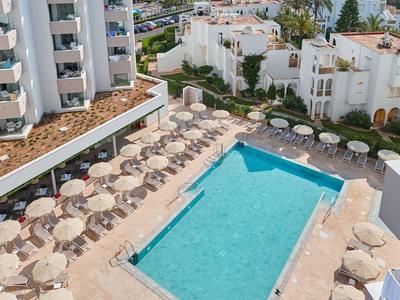 Hotel pool with sun umbrellas and sea view in the background.