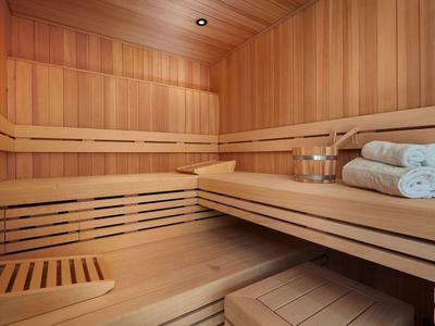 Bright wooden sauna with benches, towels, and sauna bucket with ladle.