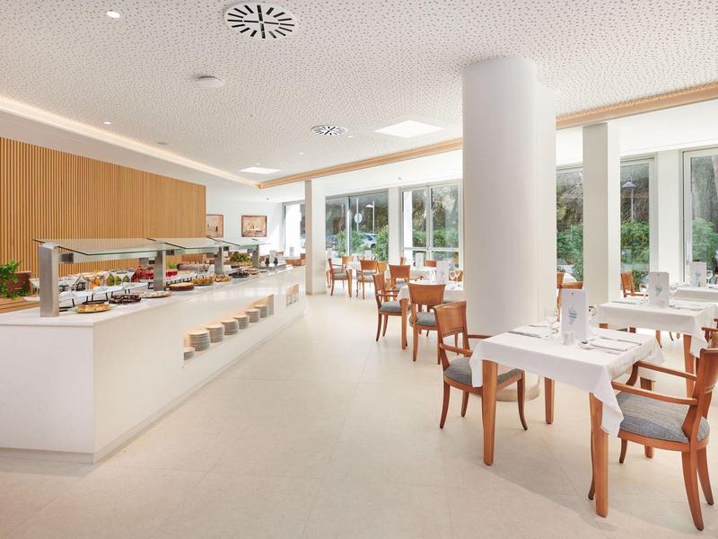 Bright, modern café with wooden furniture and large windows overlooking greenery.