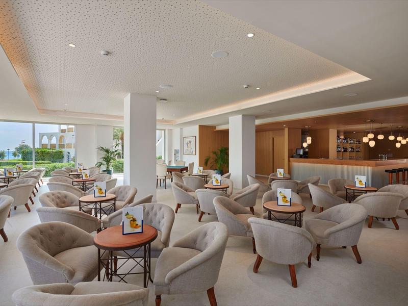 Modern hotel lounge with comfortable armchairs and large windows overlooking the garden.