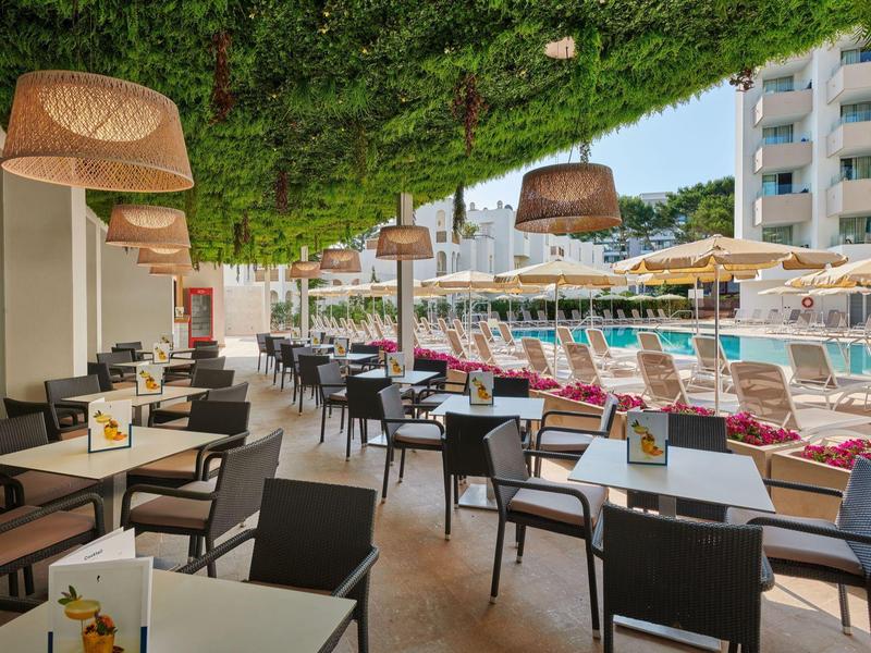 Cozy outdoor patio with tables and chairs next to a hotel pool.