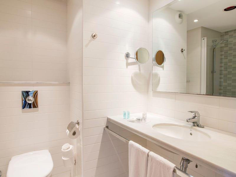 Bright bathroom with white toilet, large mirror, and sink with modern fixtures.