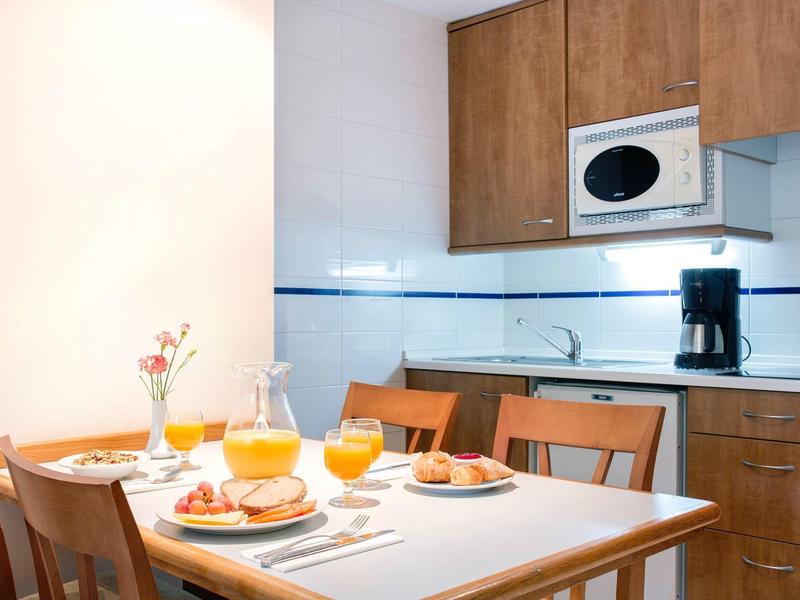 Cozy kitchen with wooden furniture, breakfast table with orange juice and pastries.